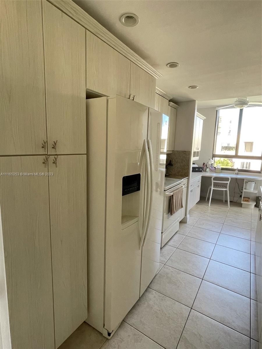 A kitchen features light wood-grain cabinetry, a white refrigerator, and a built-in desk area — 101 Crandon Blvd # 473, Key Biscayne FL 33149, KEY BISCAYNE, FL