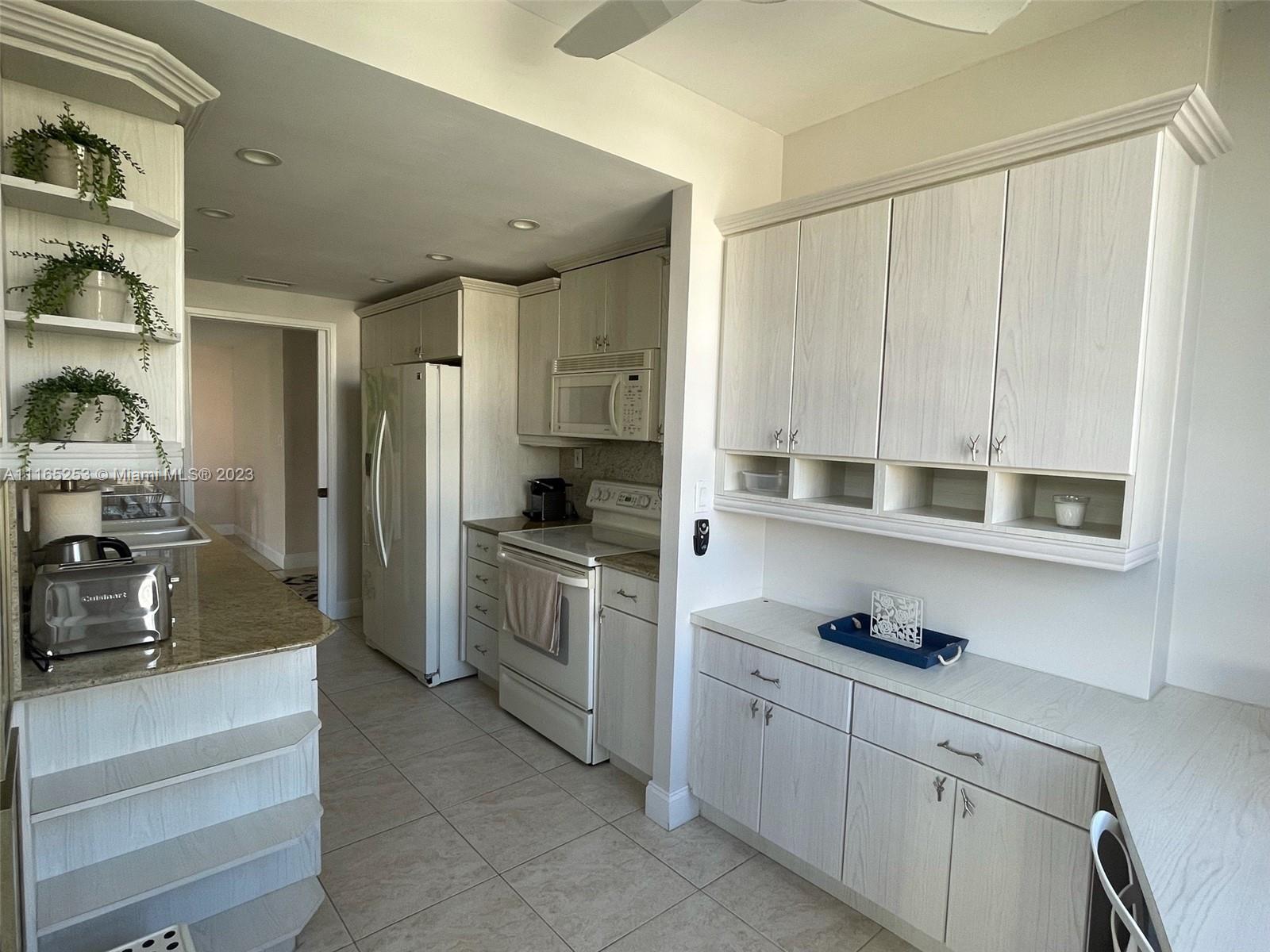 A kitchen features light wood-grain cabinets, granite countertops, and a tiled floor — 101 Crandon Blvd # 473, Key Biscayne FL 33149, KEY BISCAYNE, FL