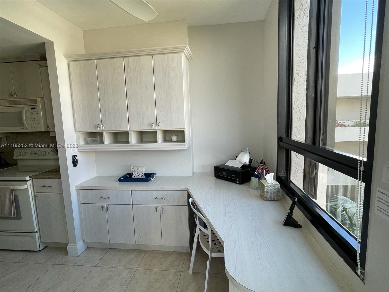 A kitchen area features light wood cabinets, a built-in desk, and a large window — 101 Crandon Blvd # 473, Key Biscayne FL 33149, KEY BISCAYNE, FL