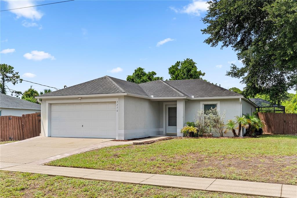 A single-story house with a white stucco exterior, a two-car garage, and a front lawn — 3270 CRAGGY BLUFF PLACE, COCOA, FL