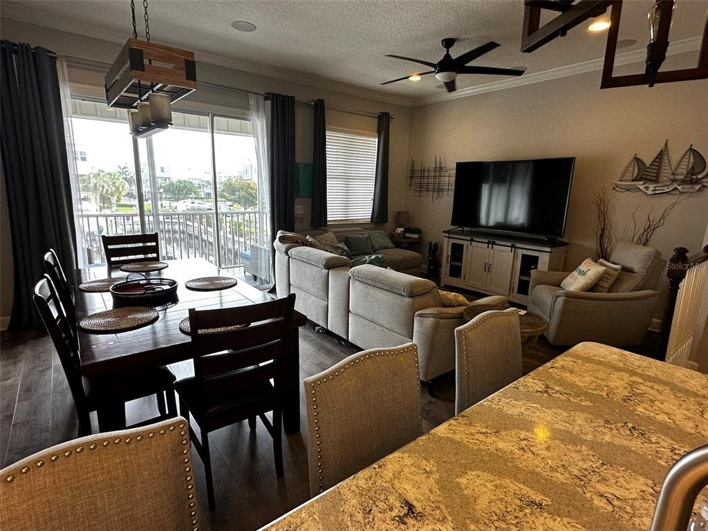 An open-concept living and dining area features a large sectional, television, and wooden dining table — 6072 MOORINGS DRIVE S, ST PETERSBURG, FL