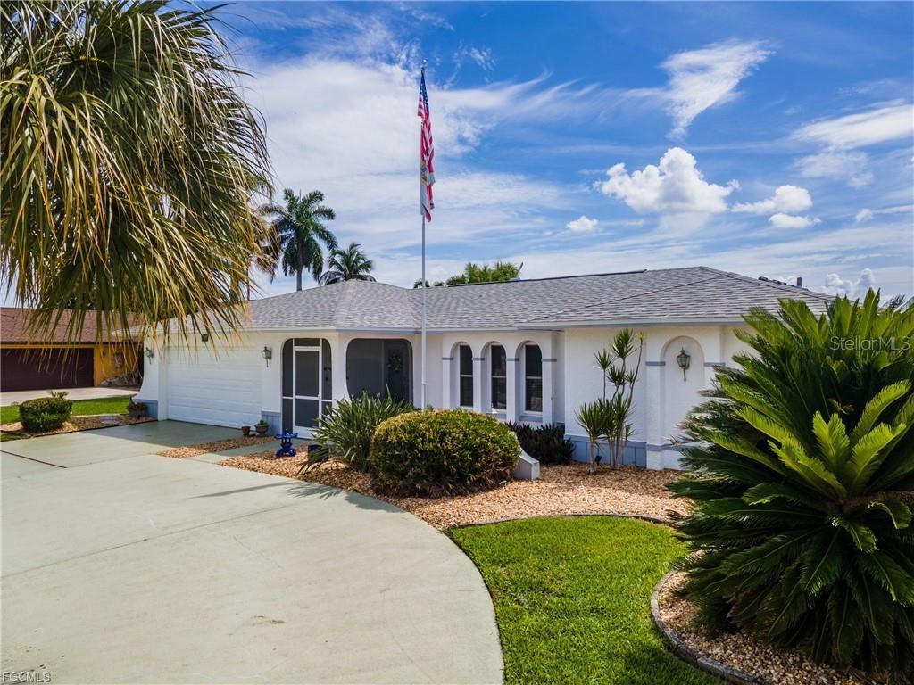 A single-story white house features a curved driveway, a flagpole, and a palm tree — 3319 SE 17TH AVENUE, CAPE CORAL, FL