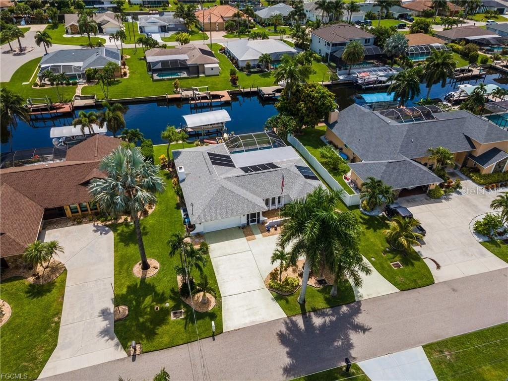 An aerial view shows a residential house with a pool, solar panels, and a canal dock — 3319 SE 17TH AVENUE, CAPE CORAL, FL