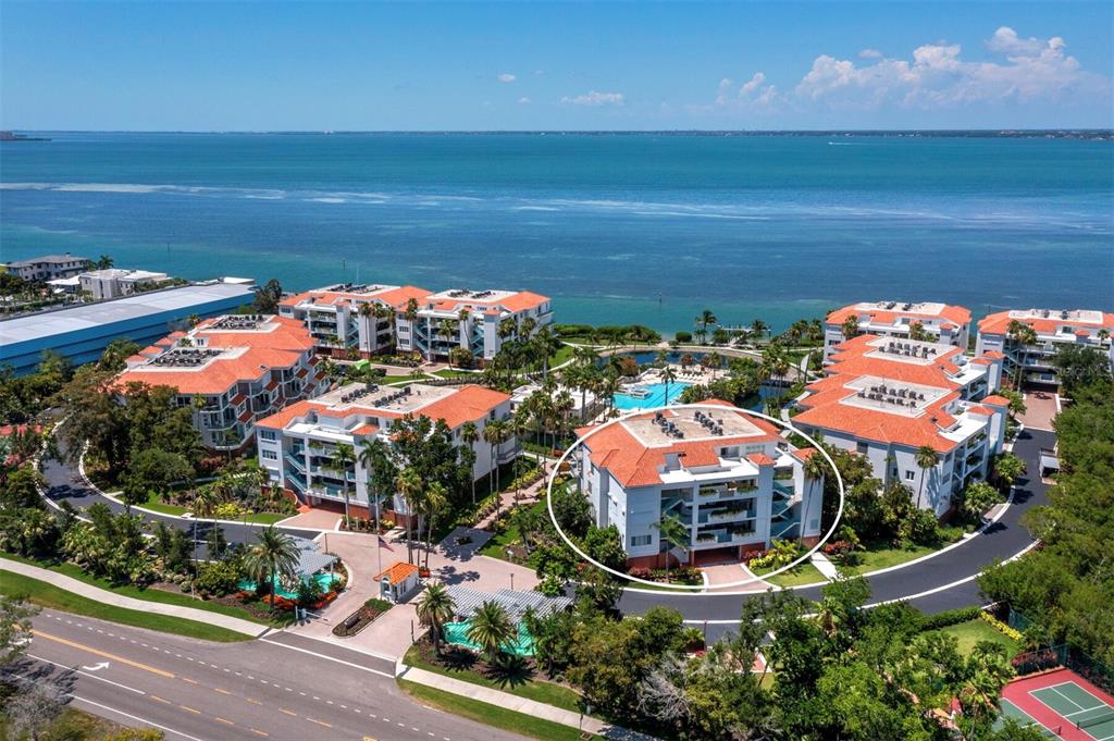 An aerial view shows a multi-story residential building complex with red-tiled roofs near water — 350 GULF OF MEXICO DRIVE UNIT 213, LONGBOAT KEY, FL