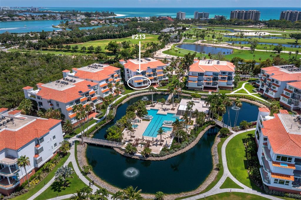 An aerial view shows a multi-story residential complex with red-tiled roofs surrounding a central pool — 350 GULF OF MEXICO DRIVE UNIT 213, LONGBOAT KEY, FL
