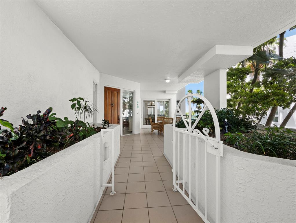A tiled walkway leads to a front door and patio area with white walls — 350 GULF OF MEXICO DRIVE UNIT 213, LONGBOAT KEY, FL
