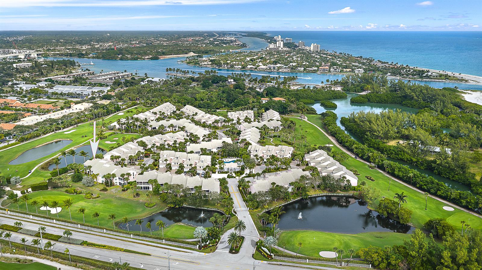An aerial view shows a residential complex surrounded by golf course greens and water features — 2608 Fairway Drive N, Jupiter FL 33477, JUPITER, FL