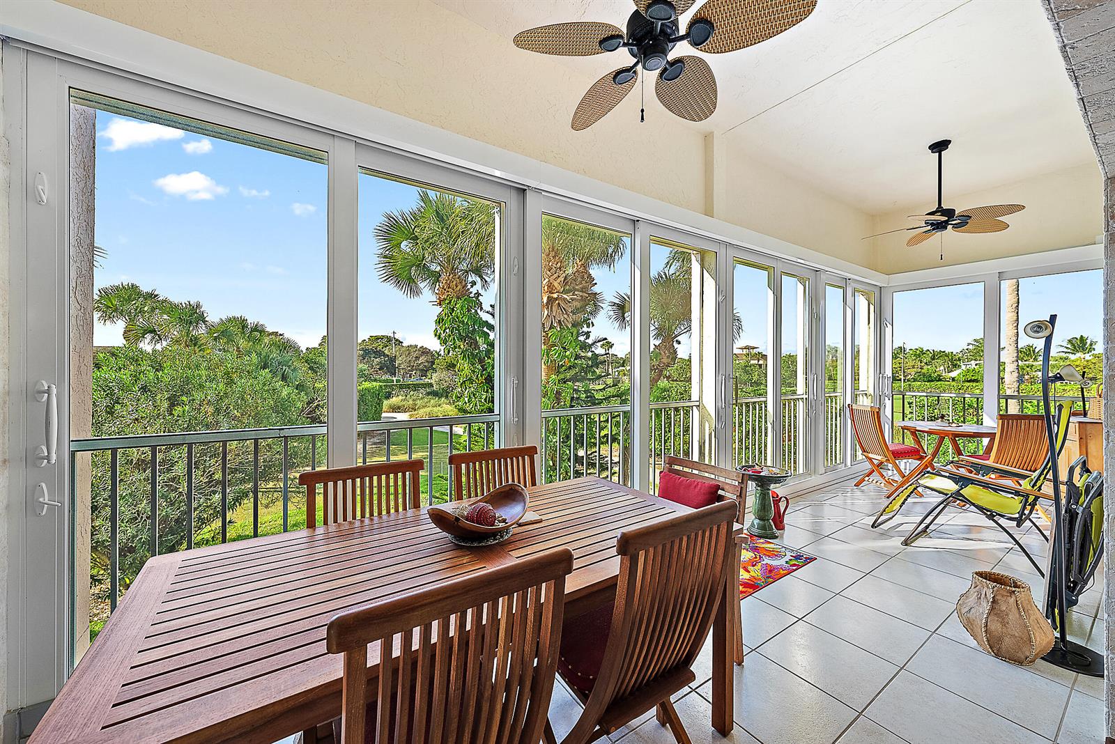 A sunroom features a wooden dining set, tile flooring, ceiling fans, and large sliding glass doors — 2608 Fairway Drive N, Jupiter FL 33477, JUPITER, FL