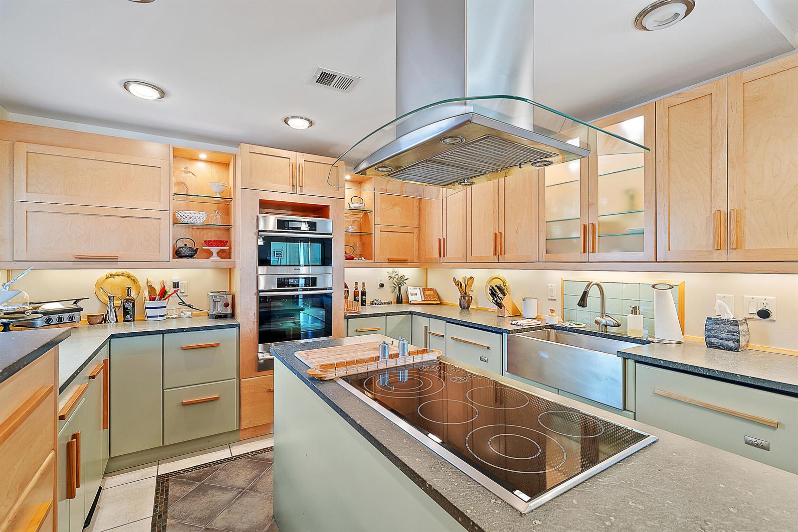A kitchen features light wood cabinets, sage green lower cabinets, a central island, and stainless appliances — 2608 Fairway Drive N, Jupiter FL 33477, JUPITER, FL