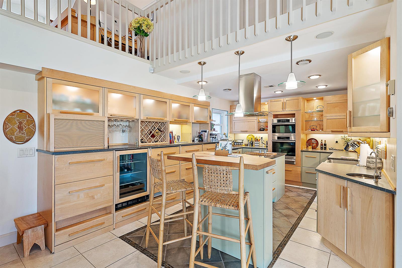 A kitchen features light wood cabinetry, a central island with bar stools, and tiled floors — 2608 Fairway Drive N, Jupiter FL 33477, JUPITER, FL