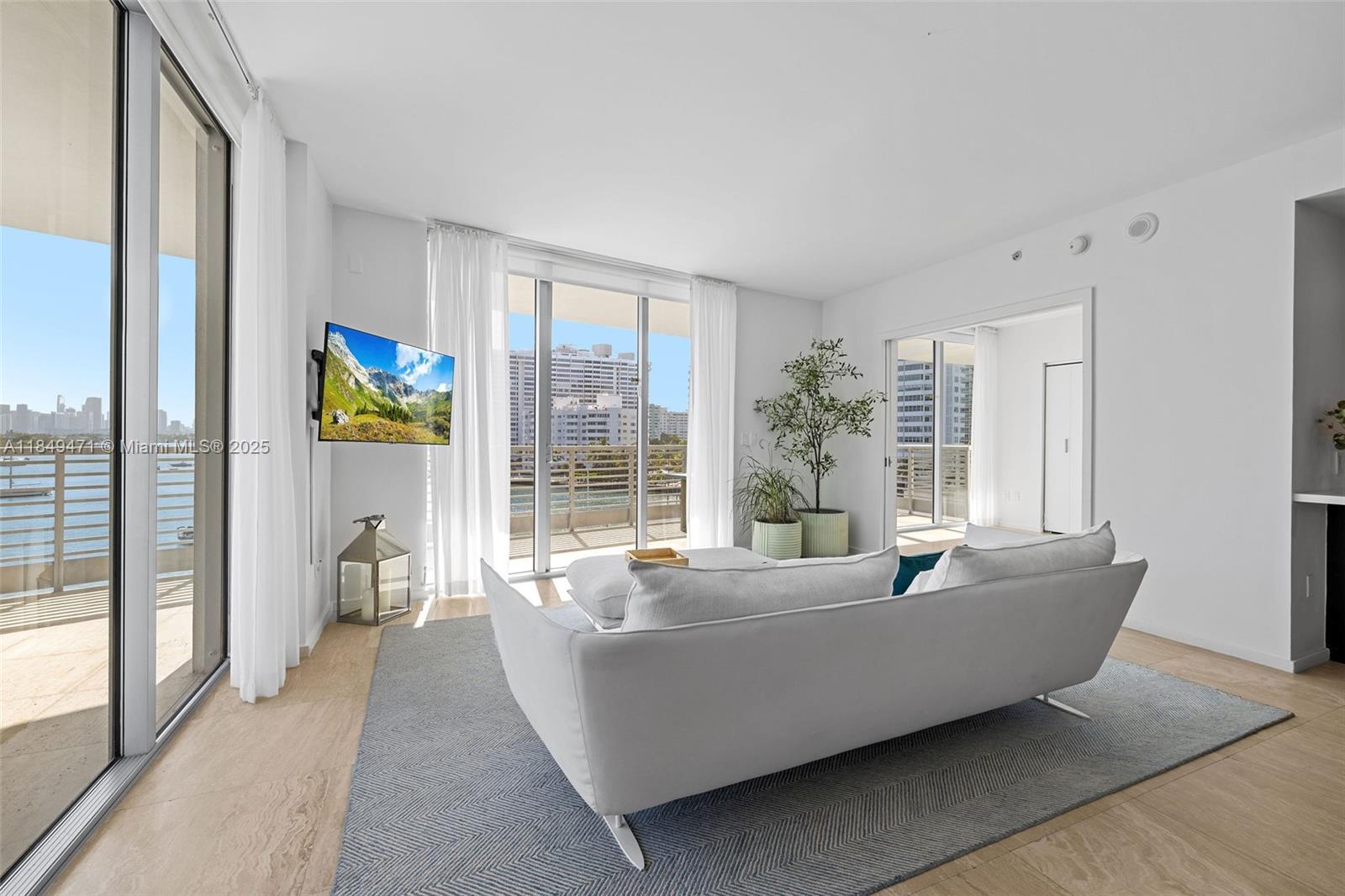 A bright living room features a white sofa, a gray rug, and a balcony view — 1445 16th St # 602, Miami Beach FL 33139, MIAMI BEACH, FL
