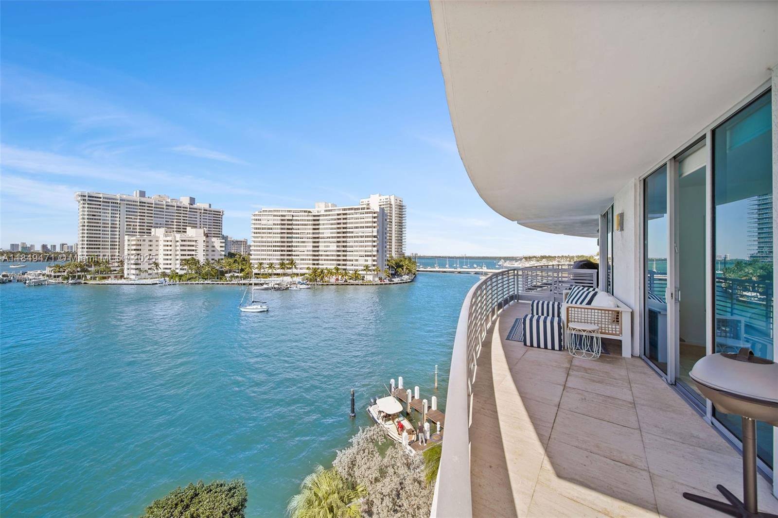 A curved balcony overlooks a blue waterway with high-rise buildings and boats in the distance — 1445 16th St # 602, Miami Beach FL 33139, MIAMI BEACH, FL