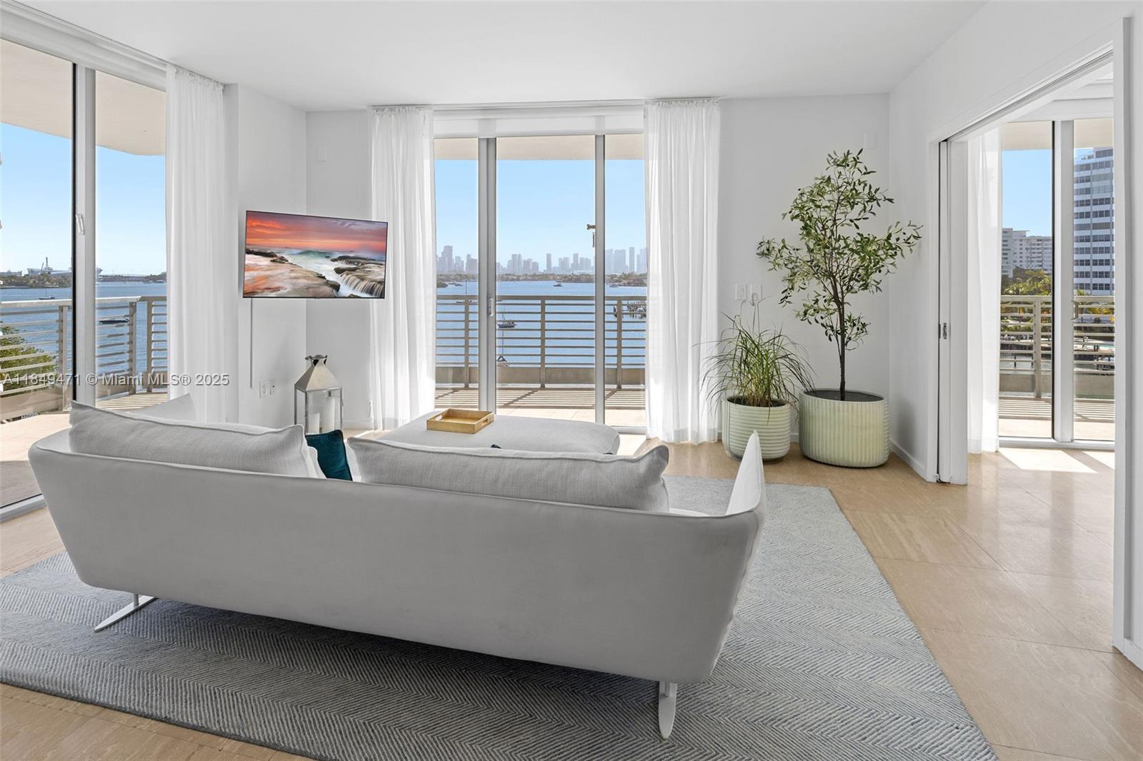 A bright living room features a white sofa, a gray rug, and sliding glass balcony doors — 1445 16th St # 602, Miami Beach FL 33139, MIAMI BEACH, FL