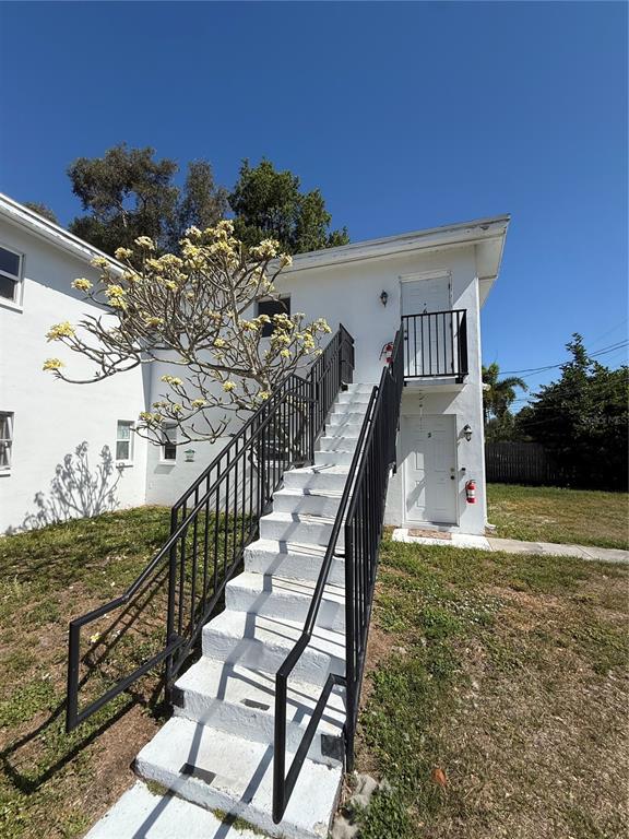 An exterior view of a white two-story apartment building with an outdoor staircase — 698 UNION STREET, DUNEDIN, FL