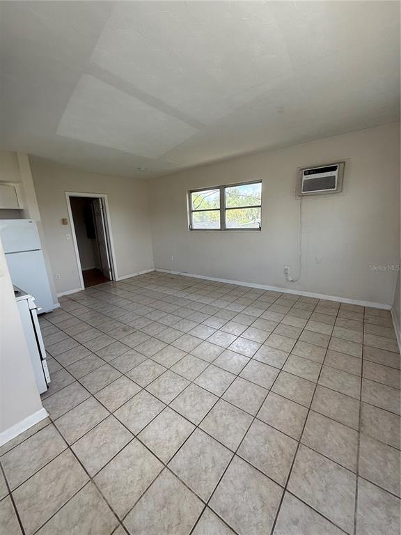 A kitchen with light-colored tile flooring, white appliances, and a window air conditioning unit — 698 UNION STREET, DUNEDIN, FL