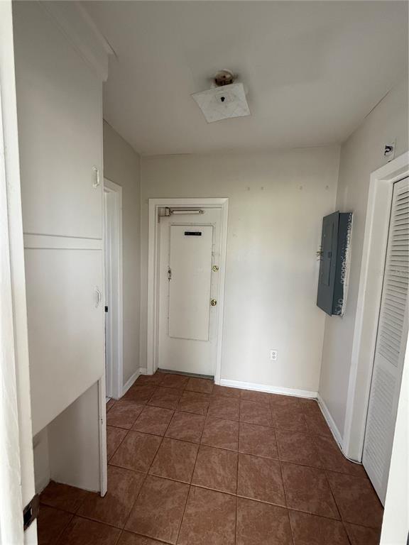 A small hallway with tiled floors, a white door, a tall cabinet, and an electrical panel — 698 UNION STREET, DUNEDIN, FL