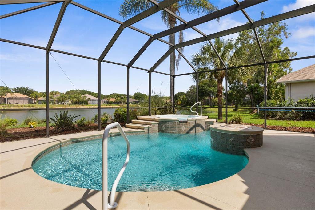 A screened-in pool and hot tub overlook a lake in a residential backyard — 57 OSPREY CIRCLE, PALM COAST, FL