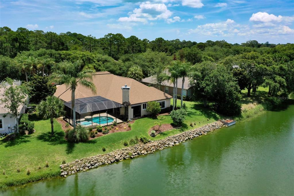 An aerial view of a house with a screened-in pool overlooking a lake — 57 OSPREY CIRCLE, PALM COAST, FL