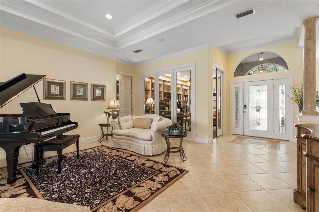 A foyer and sitting area featuring a grand piano, tile flooring, and a glass-paneled door — 57 OSPREY CIRCLE, PALM COAST, FL