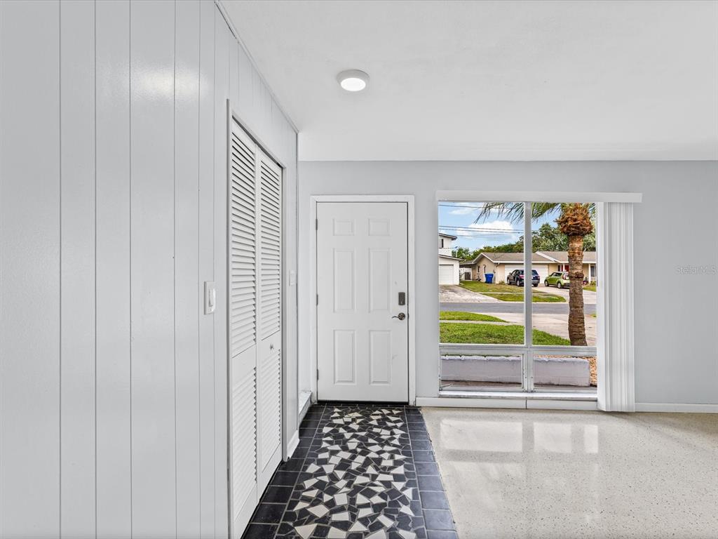 An entryway features a tiled floor, a white louvered closet door, and a front door — 865 IMPERIAL DRIVE, LARGO, FL