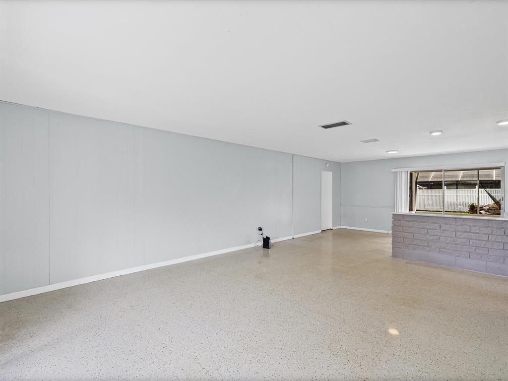 A spacious room with light gray walls, a speckled concrete floor, and a brick counter — 865 IMPERIAL DRIVE, LARGO, FL