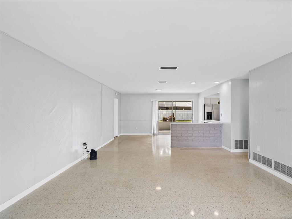 An open-concept living area features light gray walls, polished concrete floors, and a brick breakfast bar — 865 IMPERIAL DRIVE, LARGO, FL