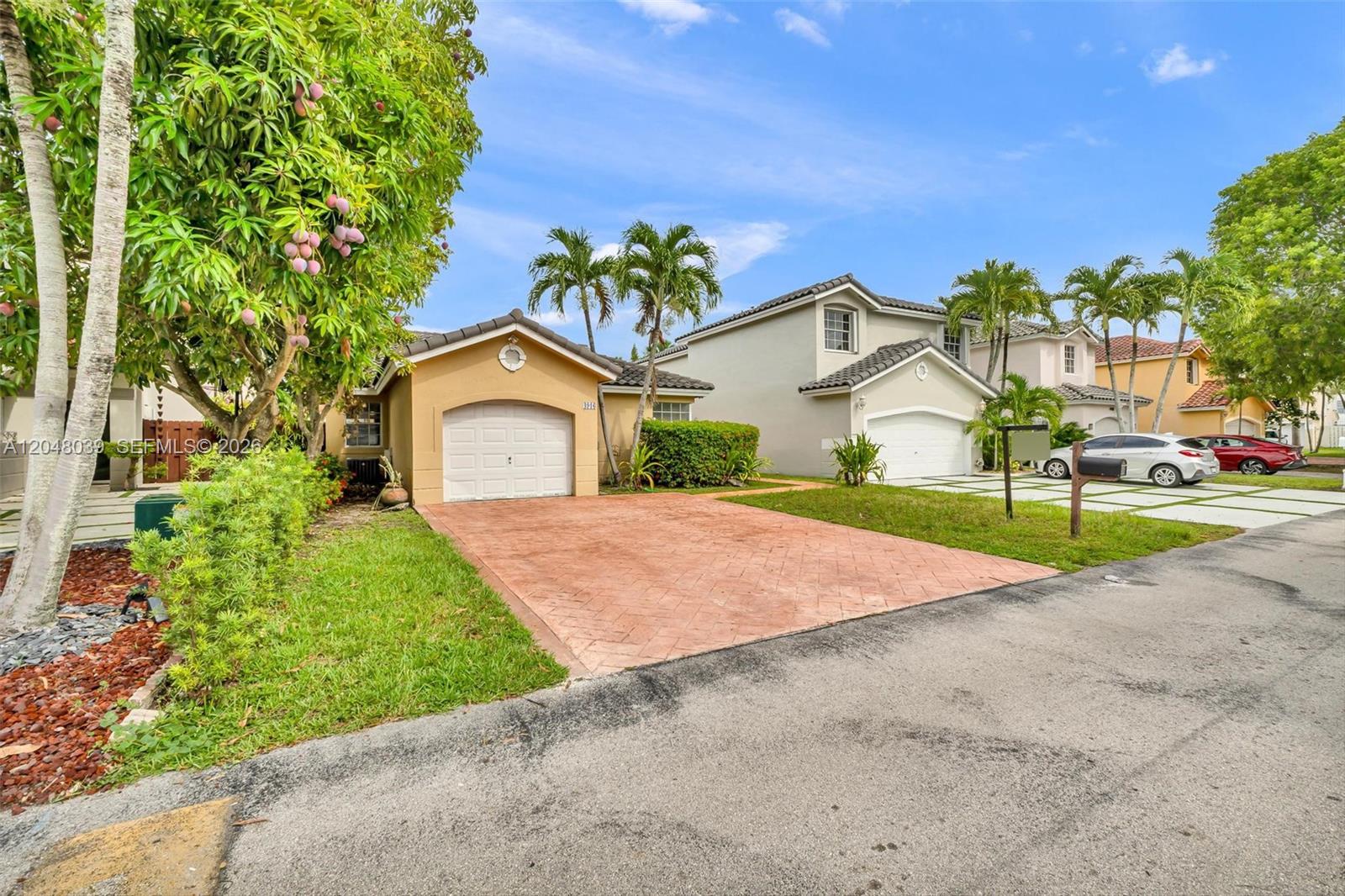 A tan single-story house with a brick driveway and a mango tree in the front yard — 4916 SW 154th Ave, Miami FL 33185, MIAMI, FL