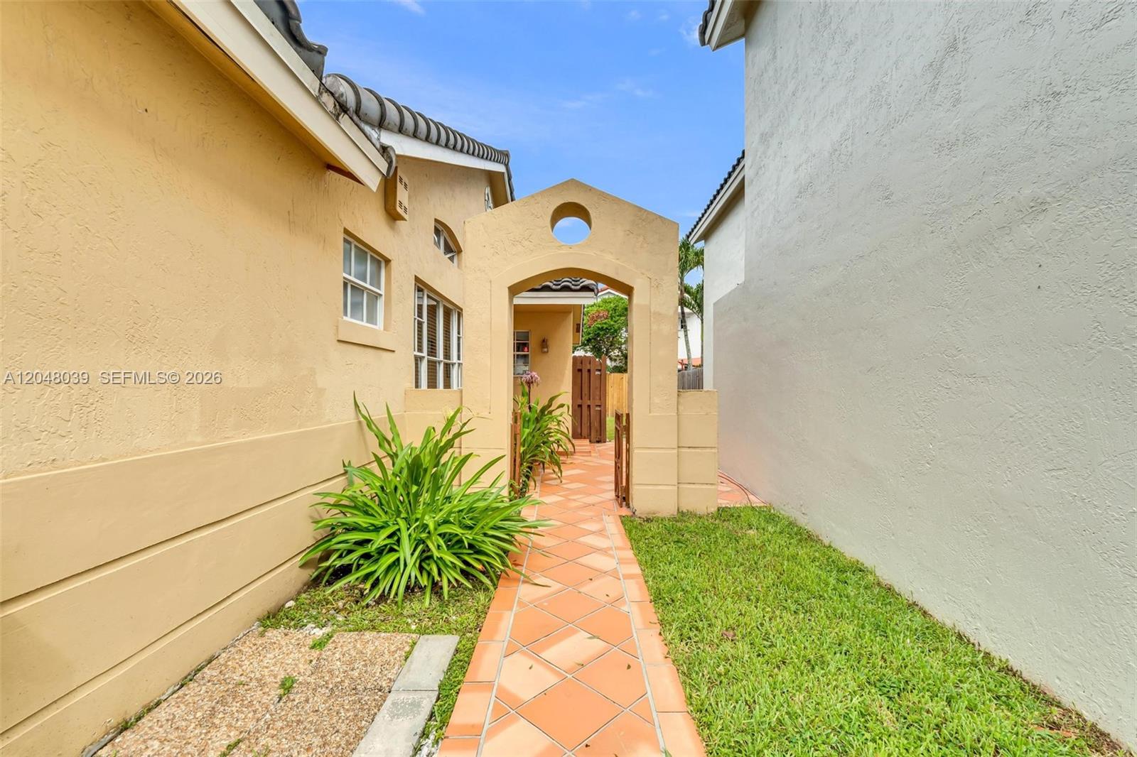 A tiled walkway leads through a stucco archway between two residential buildings — 4916 SW 154th Ave, Miami FL 33185, MIAMI, FL