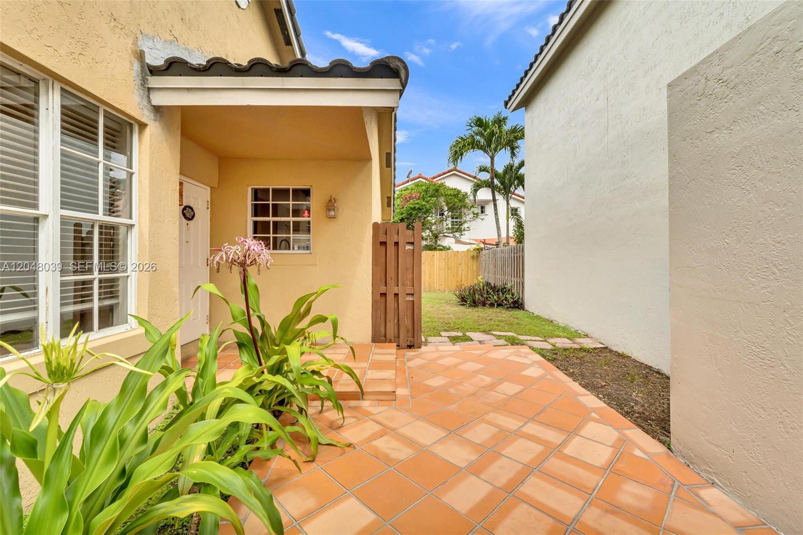 A tiled patio leads to a covered entryway beside a small grassy side yard — 4916 SW 154th Ave, Miami FL 33185, MIAMI, FL