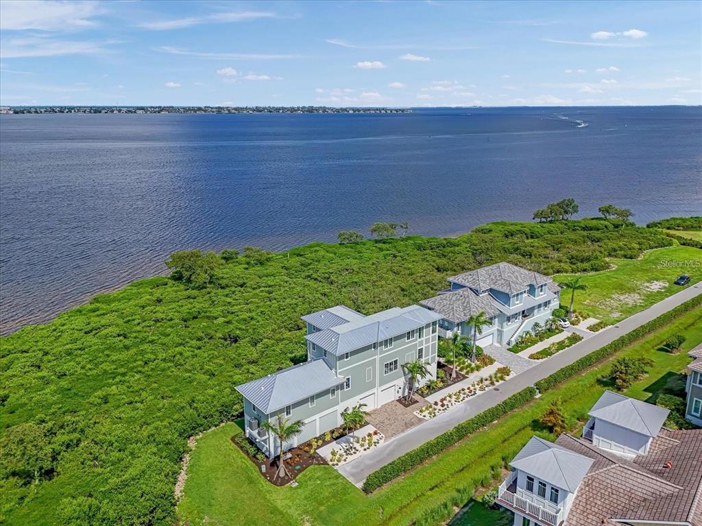 An aerial view shows two multi-story houses situated along a coastline next to a bay — 324 HARBOUR SOUND COURT, BRADENTON, FL