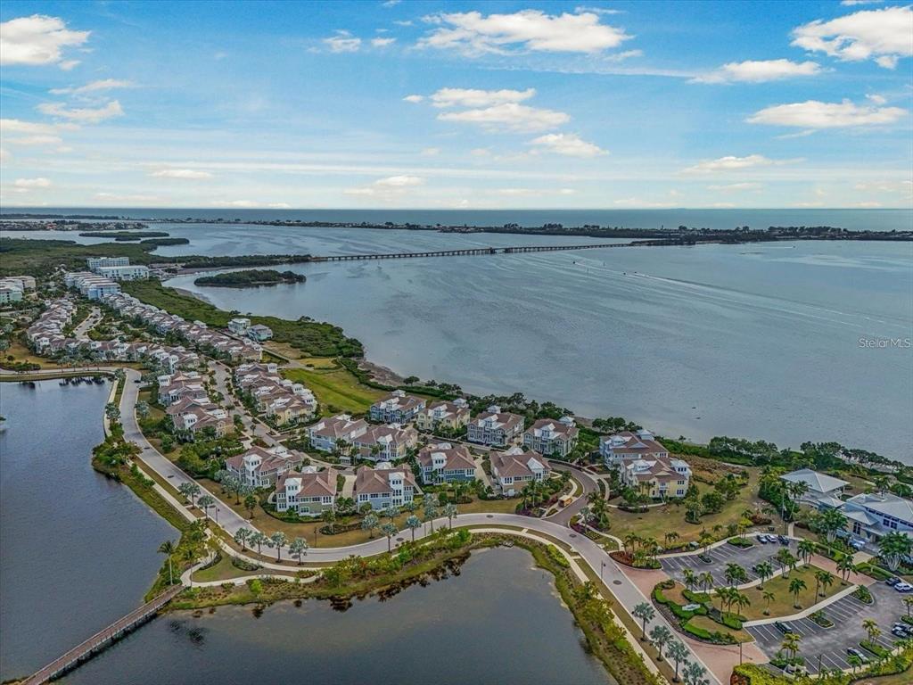 An aerial view shows a coastal residential community with multiple buildings situated near a bay — 324 HARBOUR SOUND COURT, BRADENTON, FL