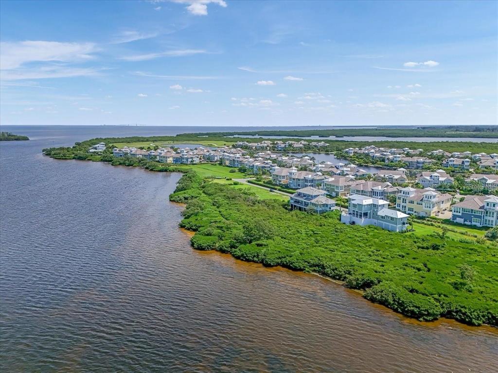 An aerial view shows a coastal residential community surrounded by lush greenery and open water — 324 HARBOUR SOUND COURT, BRADENTON, FL