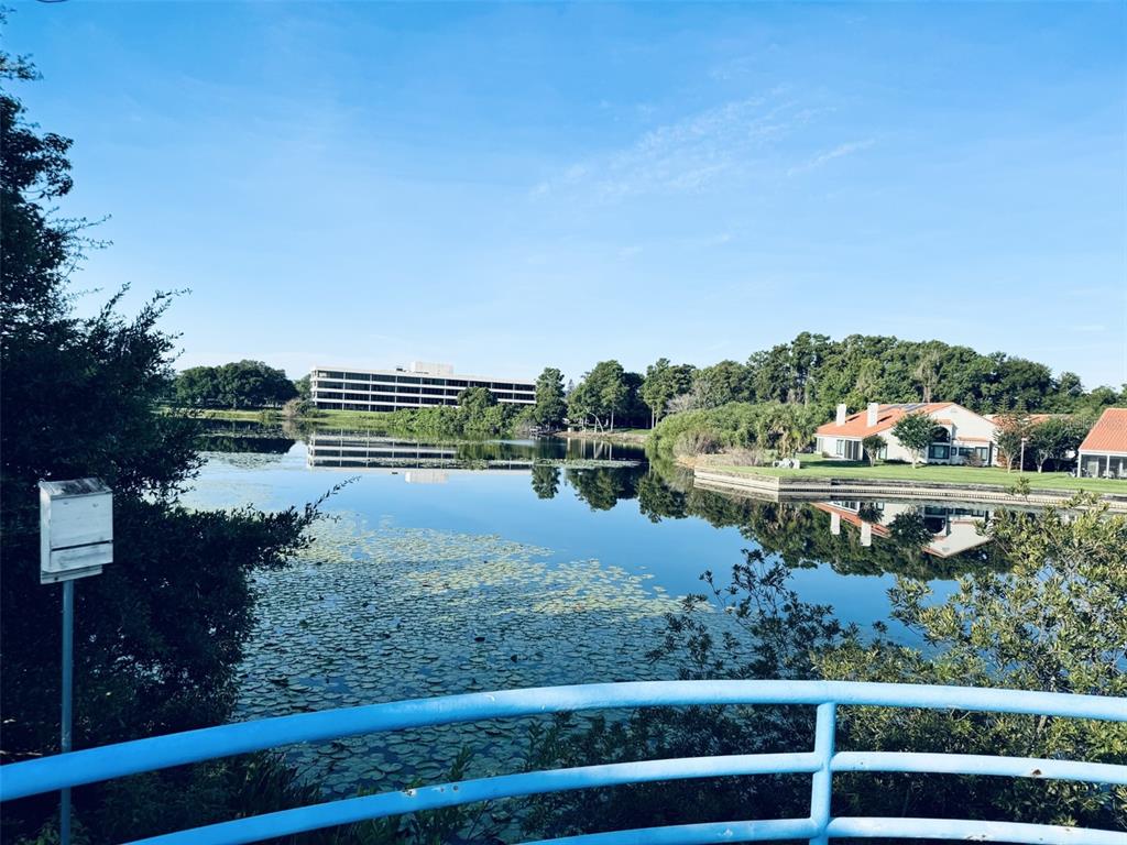 An outdoor swimming pool and hot tub overlook a lake surrounded by trees and landscaping — 1000 WINDERLEY PLACE UNIT 128, MAITLAND, FL