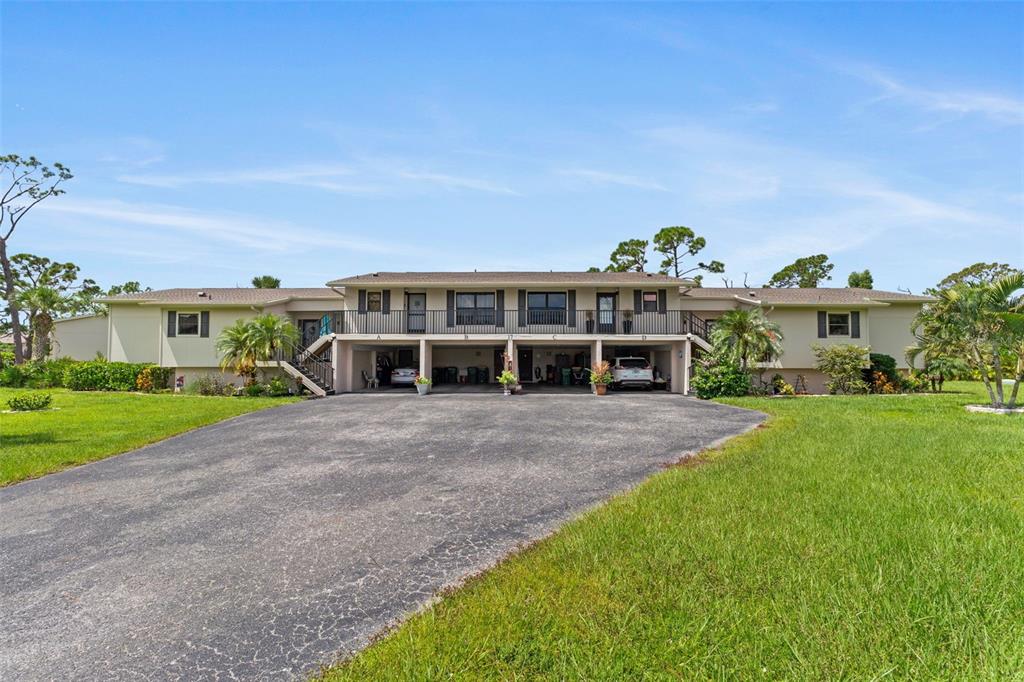 A two-story apartment building features a ground-level carport with four parking bays and an upper balcony — 4260 PLACIDA ROAD UNIT 17A, ENGLEWOOD, FL
