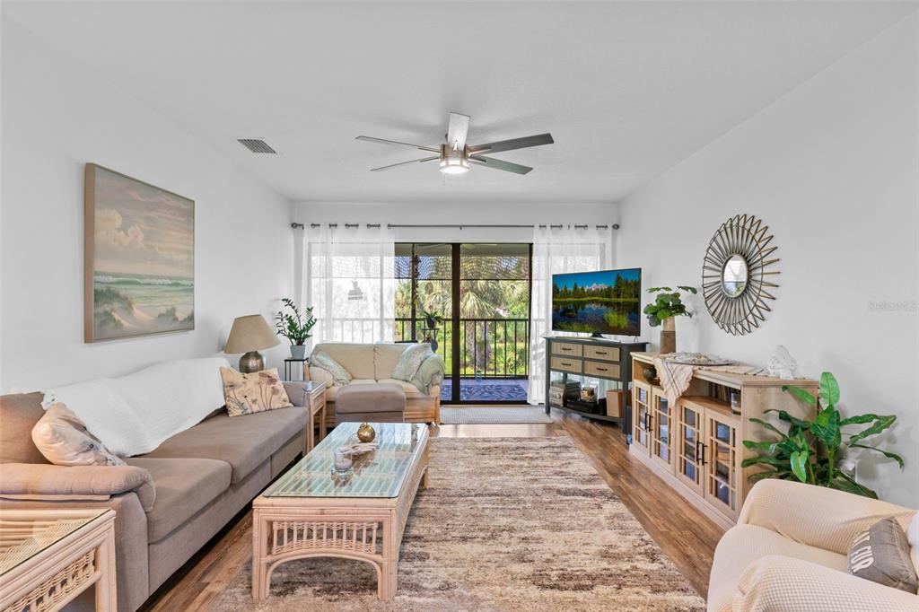 A living room features a beige sofa, a glass-topped coffee table, and a sliding glass door — 4260 PLACIDA ROAD UNIT 17A, ENGLEWOOD, FL