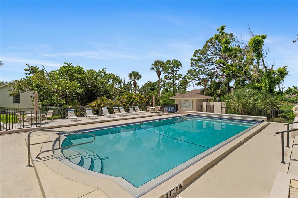 An outdoor swimming pool with lounge chairs on a concrete deck surrounded by trees — 4260 PLACIDA ROAD UNIT 17A, ENGLEWOOD, FL