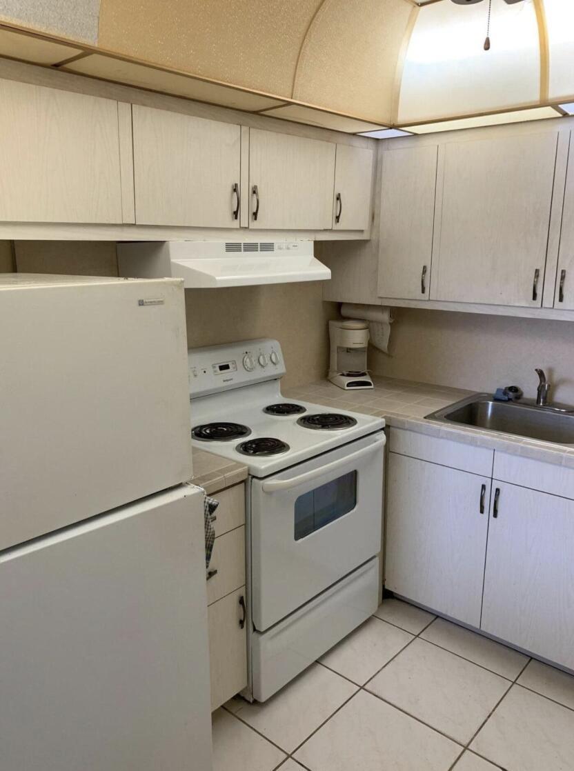 A bathroom features a white vanity with a beige sink, a mirror, and a toilet — 74 Sheffield D, West Palm Beach FL 33417, WEST PALM BEACH, FL