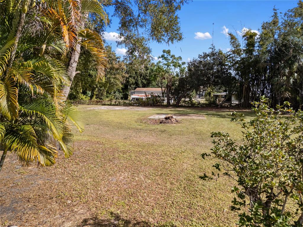 A grassy, open lot features a tree stump and scattered concrete pads under a blue sky — HOULE LOT 7 AVENUE, SARASOTA, FL