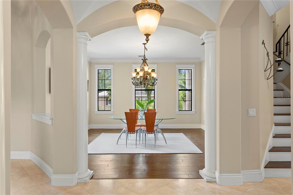 A dining room with a glass table, chandelier, and hardwood floors framed by two columns — 601 BOSPHOROUS AVENUE, TAMPA, FL