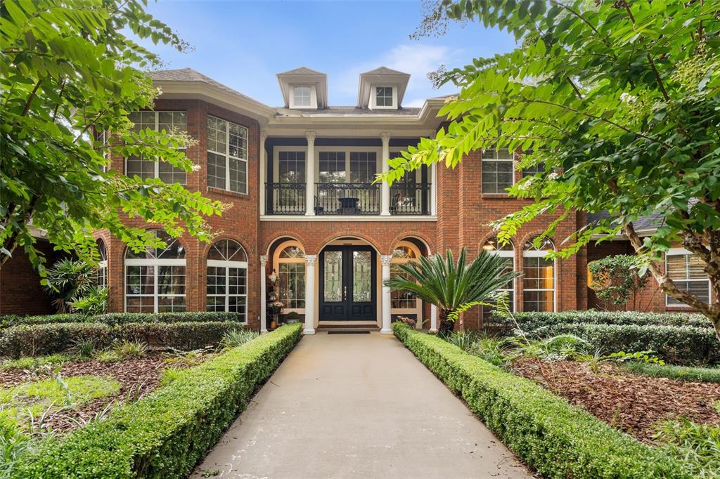 A two-story brick house with a central entrance, a second-floor balcony, and a landscaped walkway — 14408 NW 50TH PLACE, ALACHUA, FL