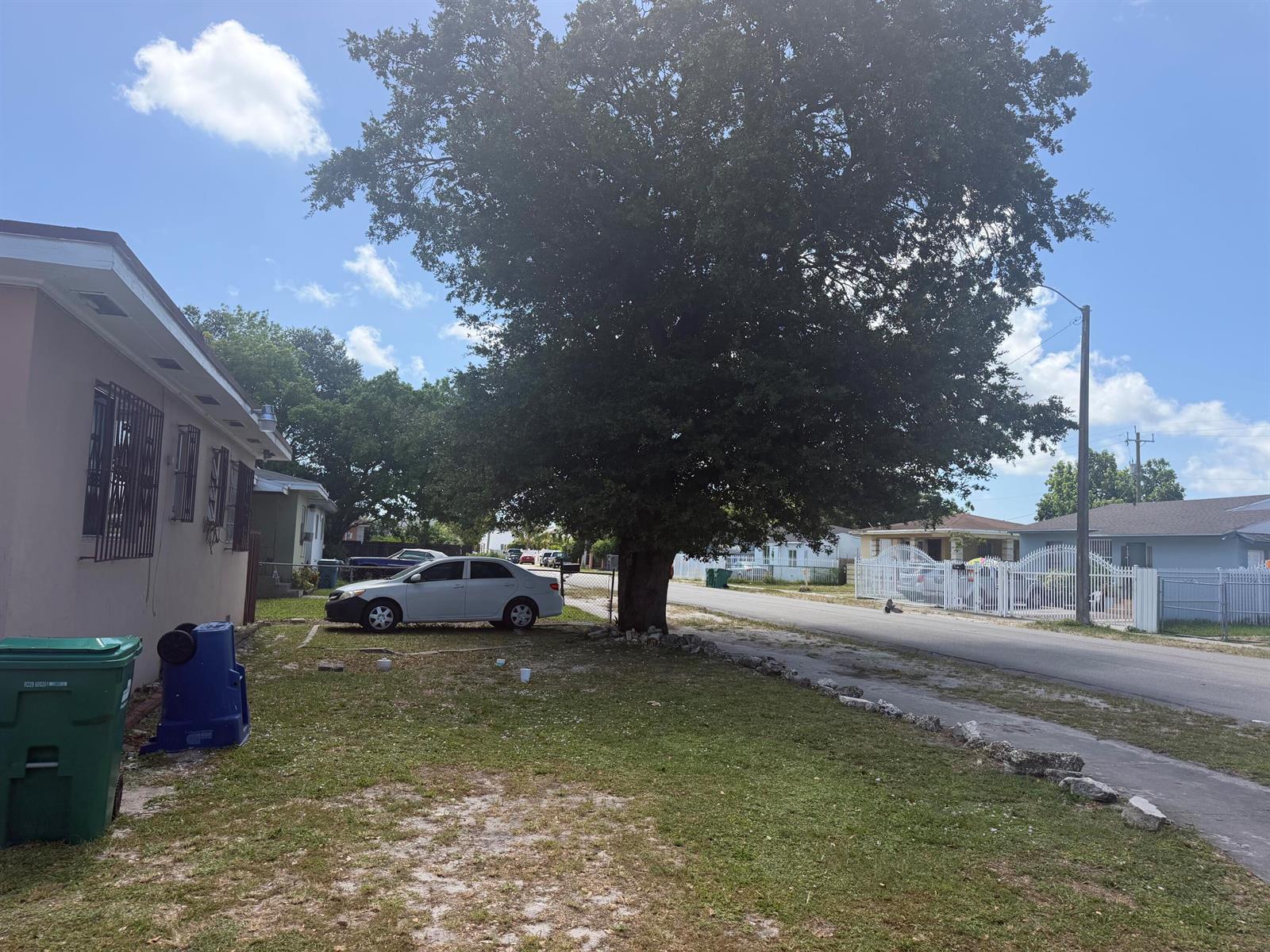 A large tree stands in the front yard of a house next to a parked car — 7803 NW 8th Avenue, Miami FL 33150, MIAMI, FL