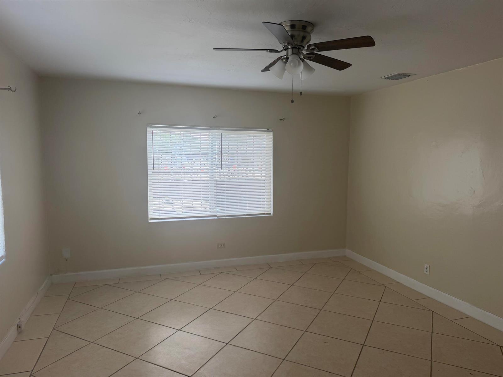 An empty room features beige walls, a ceiling fan, and light-colored diagonal floor tiles — 7803 NW 8th Avenue, Miami FL 33150, MIAMI, FL