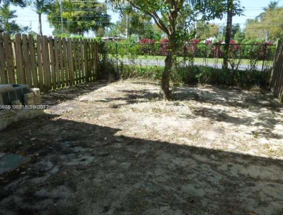 A backyard area features a wooden fence, a single tree, and sparse ground cover — 641 E Mowry Ct, Homestead FL 33030, HOMESTEAD, FL