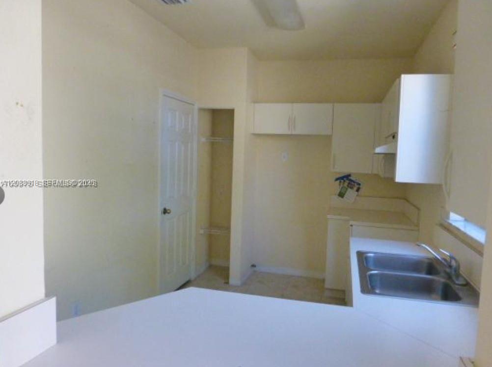 A kitchen features white cabinets, a double-basin sink, and an adjacent pantry closet — 641 E Mowry Ct, Homestead FL 33030, HOMESTEAD, FL