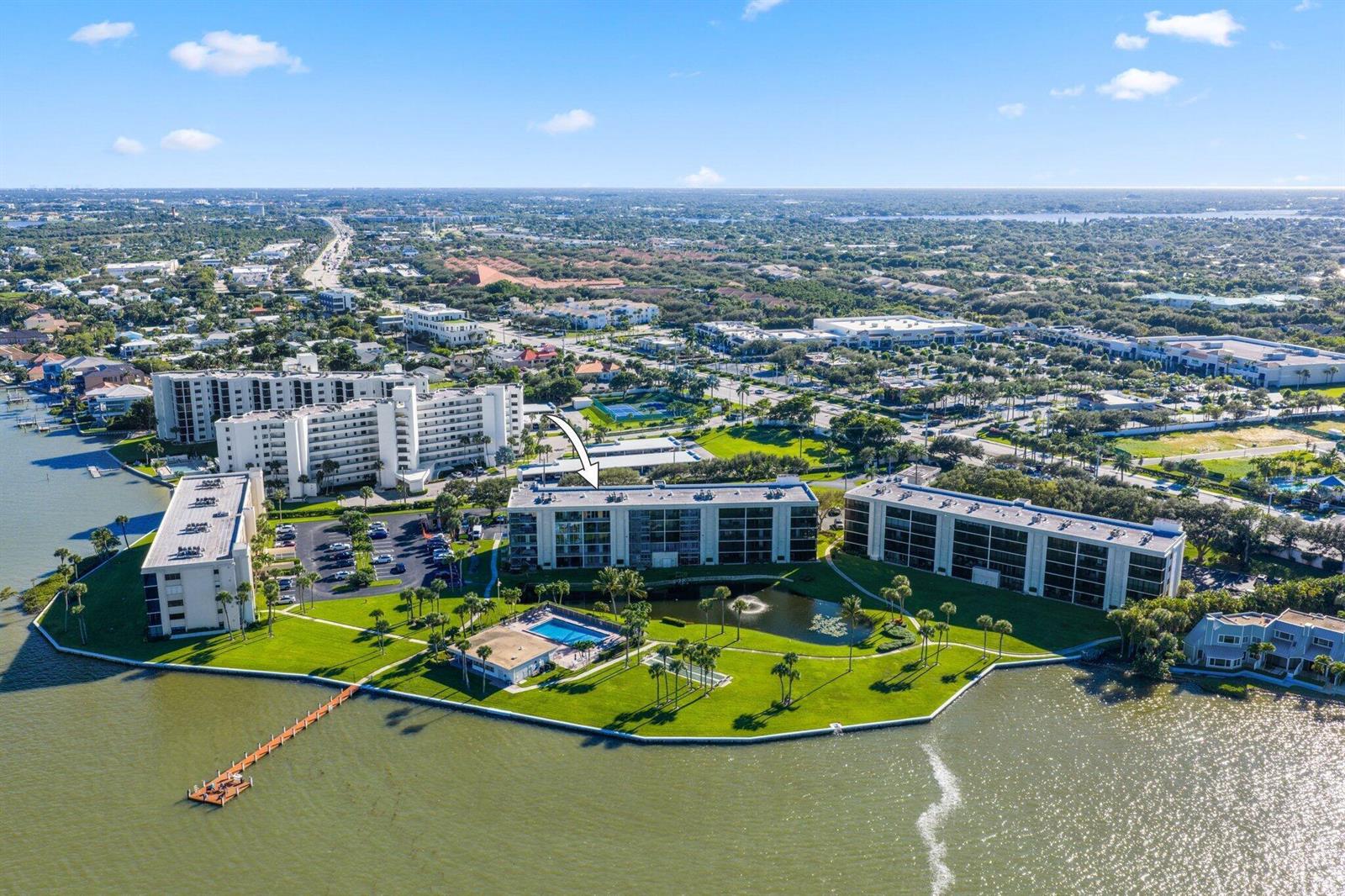 An aerial view shows several multi-story apartment buildings situated along a waterfront with a pool — 200 Intracoastal Place # 206, Jupiter FL 33469, JUPITER, FL