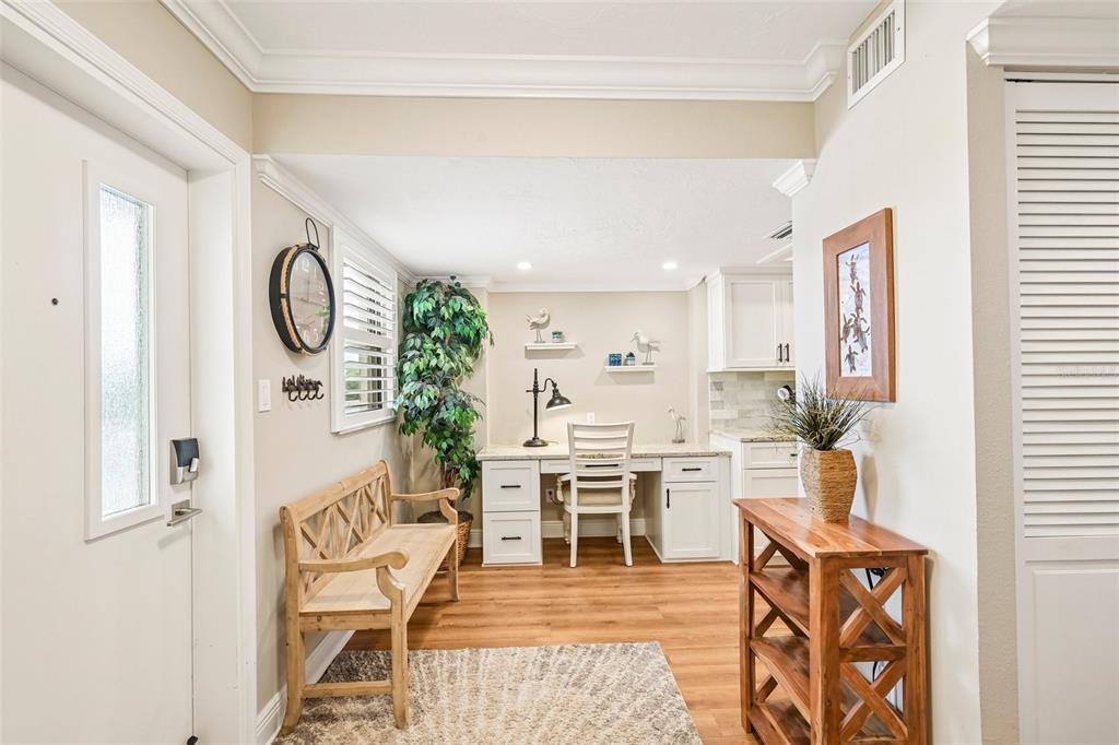 A bright entryway features a wooden bench, a built-in desk, and light wood-look flooring — 5760 MIDNIGHT PASS ROAD UNIT #209D, SARASOTA, FL
