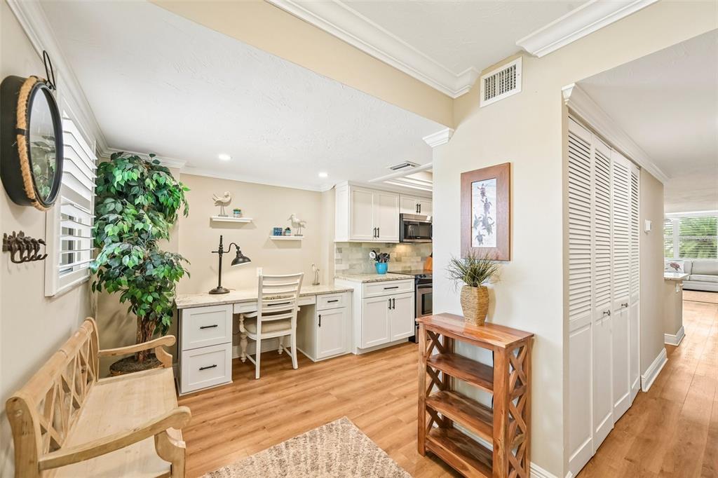 A kitchen area features white cabinets, a built-in desk, and light wood-look flooring — 5760 MIDNIGHT PASS ROAD UNIT #209D, SARASOTA, FL