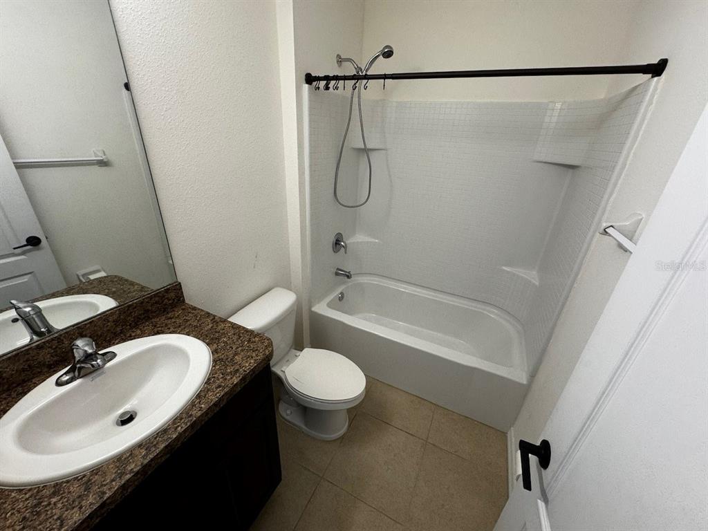 A bathroom features a vanity with a granite countertop, a toilet, and a shower-tub combination — 10526 WHISPERING HAMMOCK DRIVE, RIVERVIEW, FL