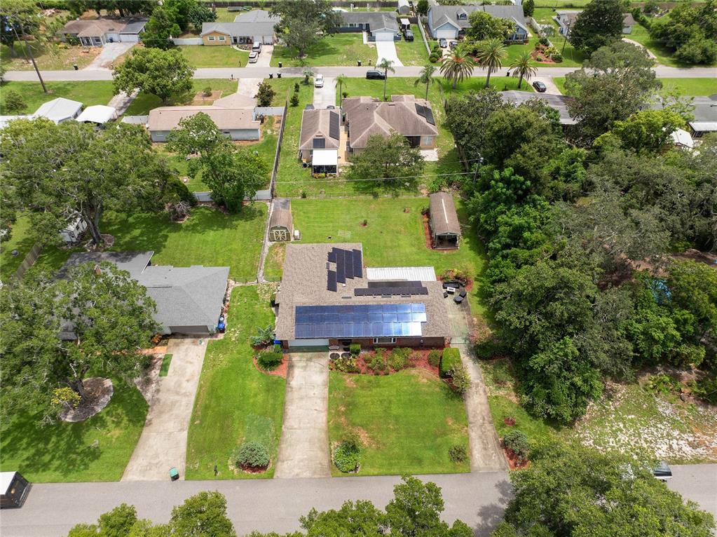 An aerial view shows a house with solar panels on the roof and a large yard — 1435 PAULA DRIVE, APOPKA, FL