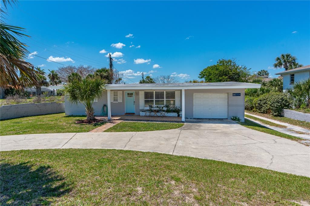 A single-story house with a light blue door, a white garage, and a concrete driveway — 2908 S PENINSULA DRIVE, DAYTONA BEACH, FL